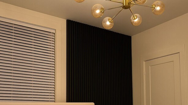 A neatly made bed with a large decorative pillow, a bedside table with a vase, and a modern chandelier. - 3 KING Beds & Free parking • Central Place (Pittsburgh)