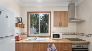 Une cuisine équipée d’un réfrigérateur, d’un four à micro-ondes, d’un four traditionnel, de meubles de rangement en bois, d’une fenêtre avec vue et d’un évier.