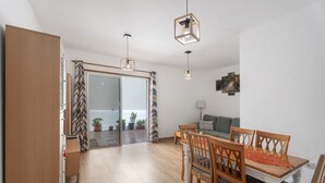 Un espace de vie moderne comprenant un coin repas, un canapé et une vue sur l’extérieur grâce à une porte vitrée.