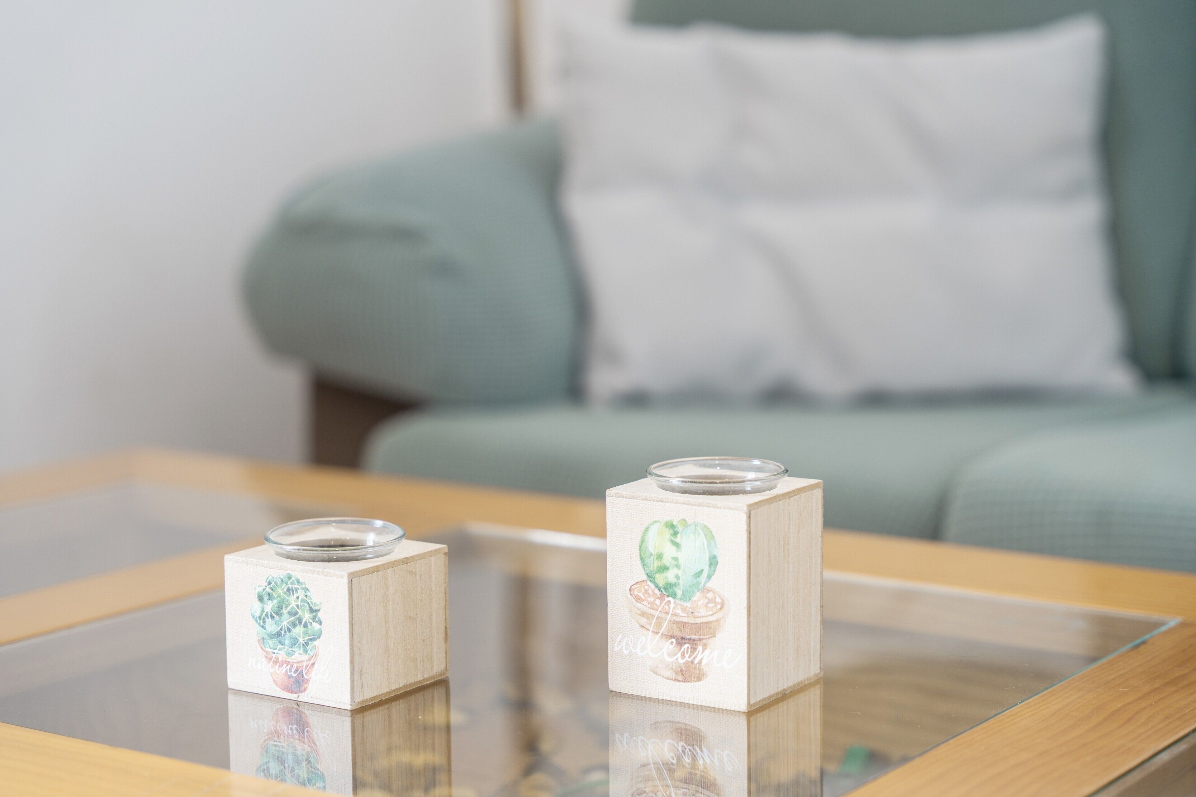 Deux chandeliers en bois ornés d’un motif de cactus, posés sur une table en verre.