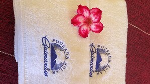 Two folded towels with embroidered logos and a red flower.