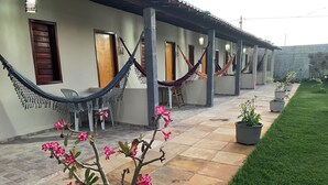A covered outdoor area with hammocks, potted plants, and a tiled walkway.