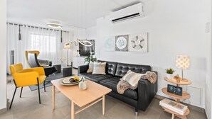 A modern living room with a sofa, chairs, a coffee table, and a TV.