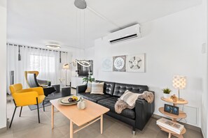 A modern living room with a sofa, chairs, a coffee table, and a TV.
