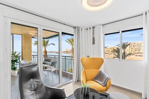 A modern room with a balcony, a sofa, a chair, and a table with a plant.