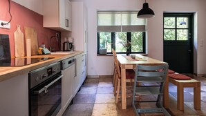 Una cucina moderna con un piano di lavoro in legno, elettrodomestici in acciaio inossidabile e un'area pranzo con tavolo e sedie.