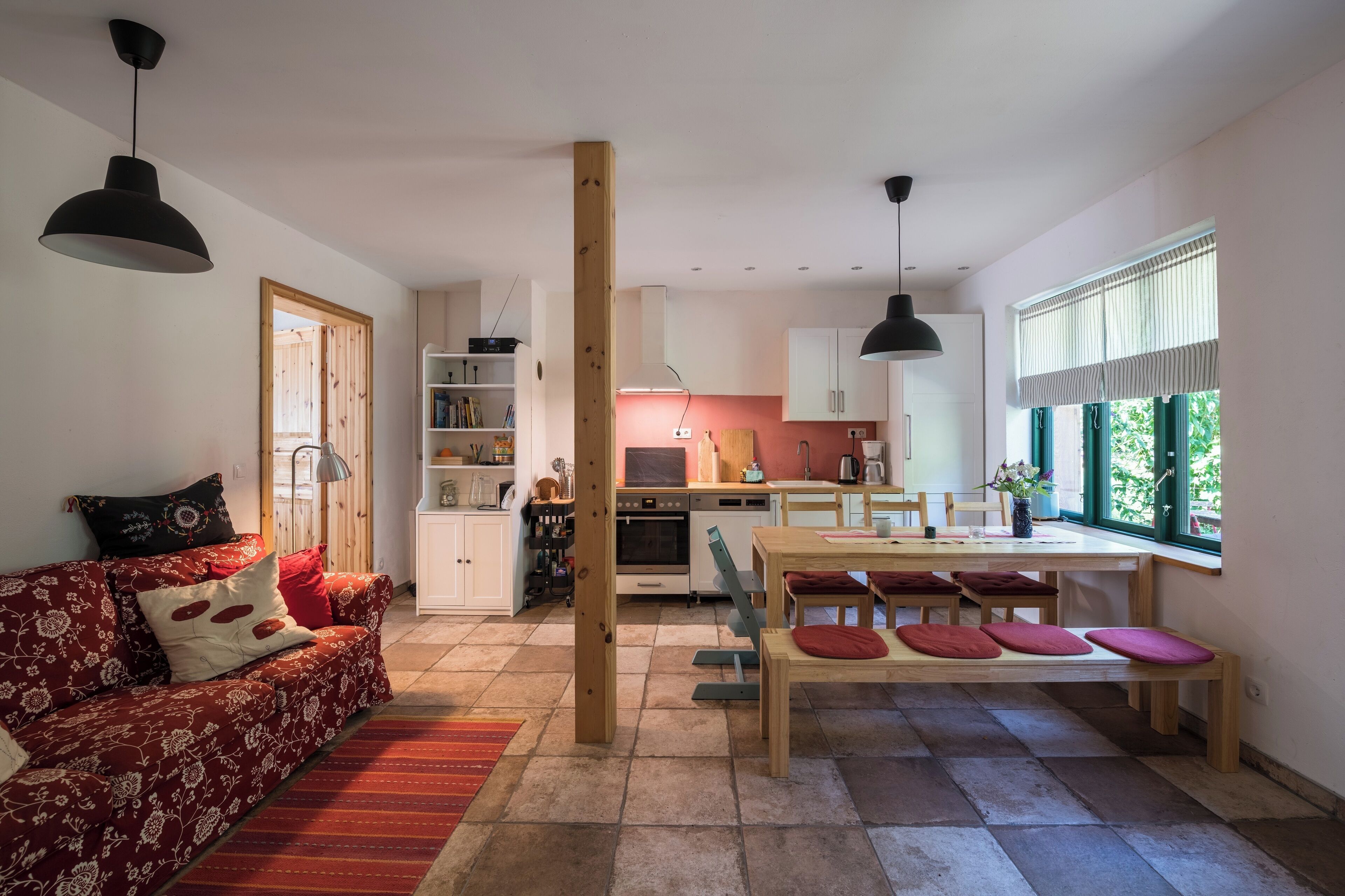 A modern living room with a sofa, dining table, and kitchen area.