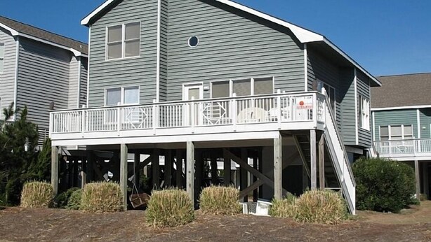 A two-story house with a balcony and a small porch. - ISLAND PARK - SECOND ROW! AVAILABLE NOW! By Williamson Realty (Ocean Isle Beach)