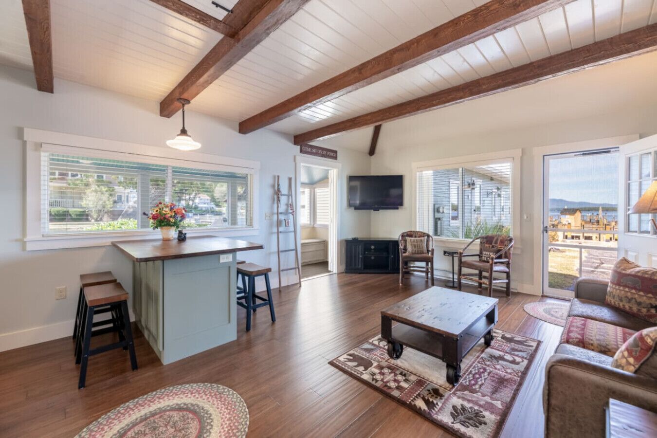 A spacious living area with a wooden ceiling, a bar area, and a large window offering a view of the outdoors.