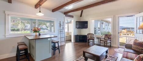 A spacious living area with a wooden ceiling, a bar area, and a large window offering a view of the outdoors.