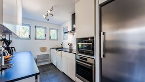 A modern kitchen with stainless steel appliances, white cabinetry, and a blue countertop.