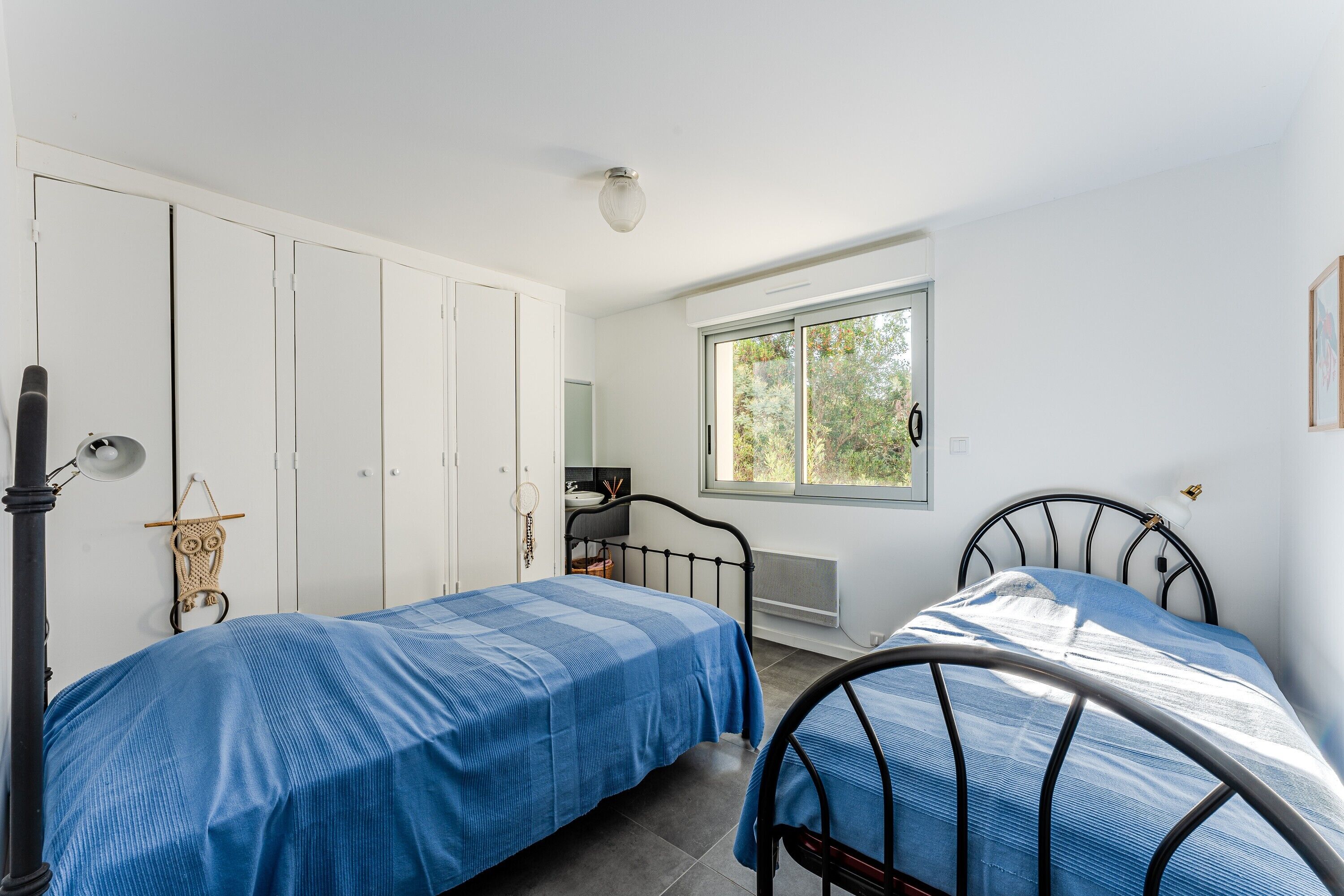 Een slaapkamer met twee bedden, een kledingkast, een raam en een radiator.
