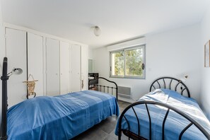 Een slaapkamer met twee bedden, een kledingkast, een raam en een radiator.