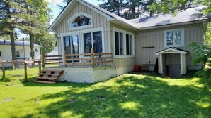 A single-story house with a porch, a fenced yard, and a small shed.