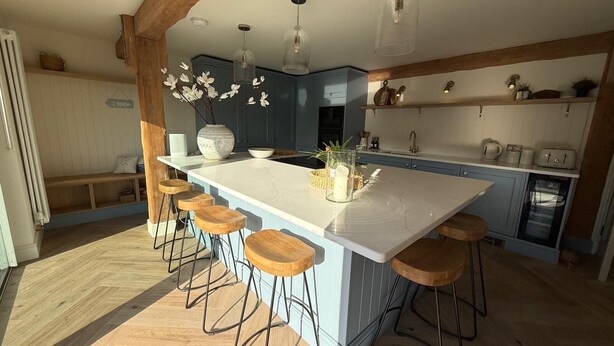 A kitchen with a large island, bar stools, a built-in oven, and a refrigerator. - Luxurious and Spacious Seaside Sanctuary (Criccieth)