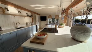 A modern kitchen with a marble countertop, a large vase, and a bowl of fruit. - Luxurious and Spacious Seaside Sanctuary (Criccieth)