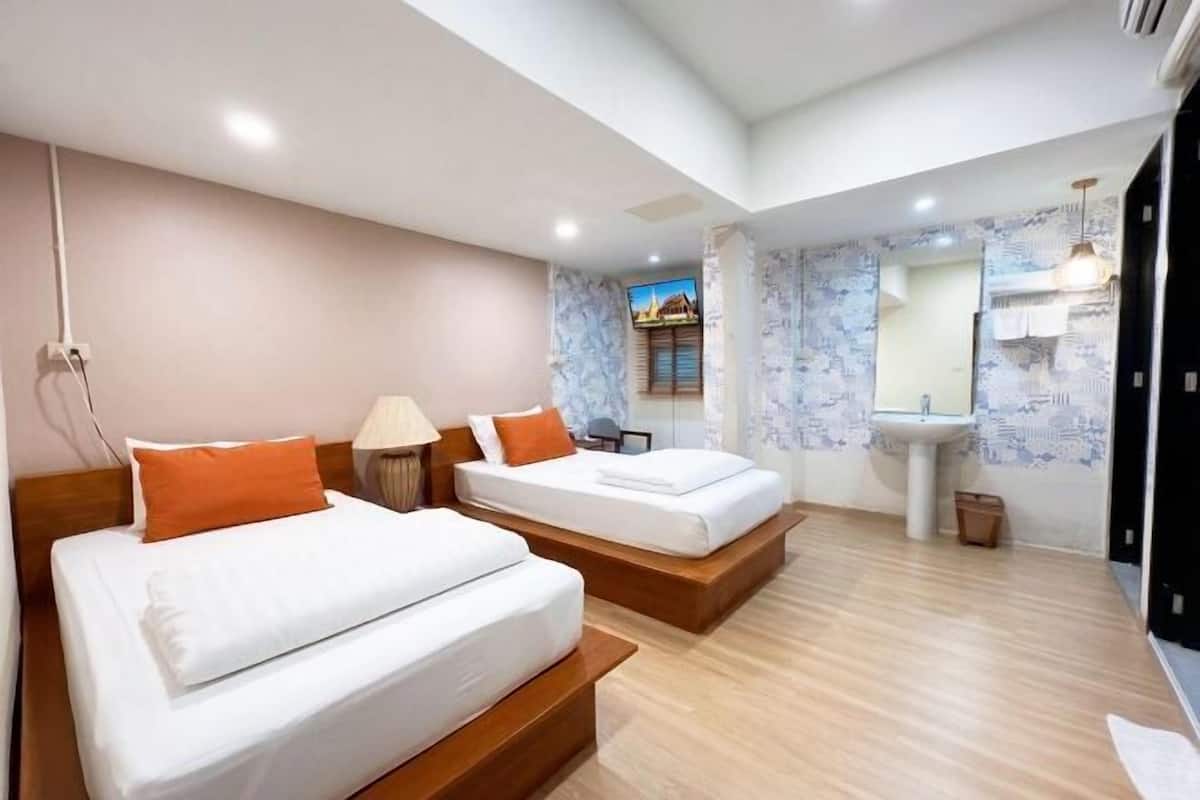 A hotel room with two beds, a bathroom with a sink, and a large mirror.
