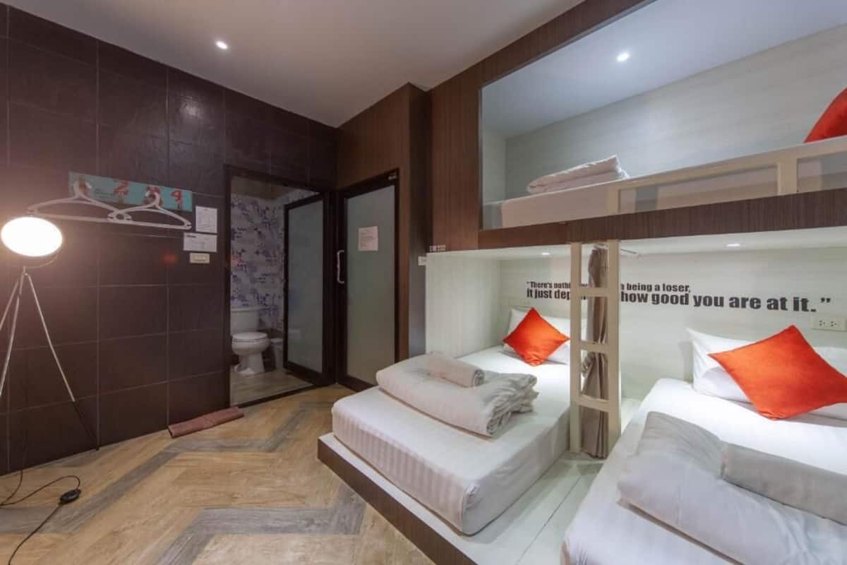 A hotel room with two beds, a mirror, a light fixture, and a motivational quote on the wall.