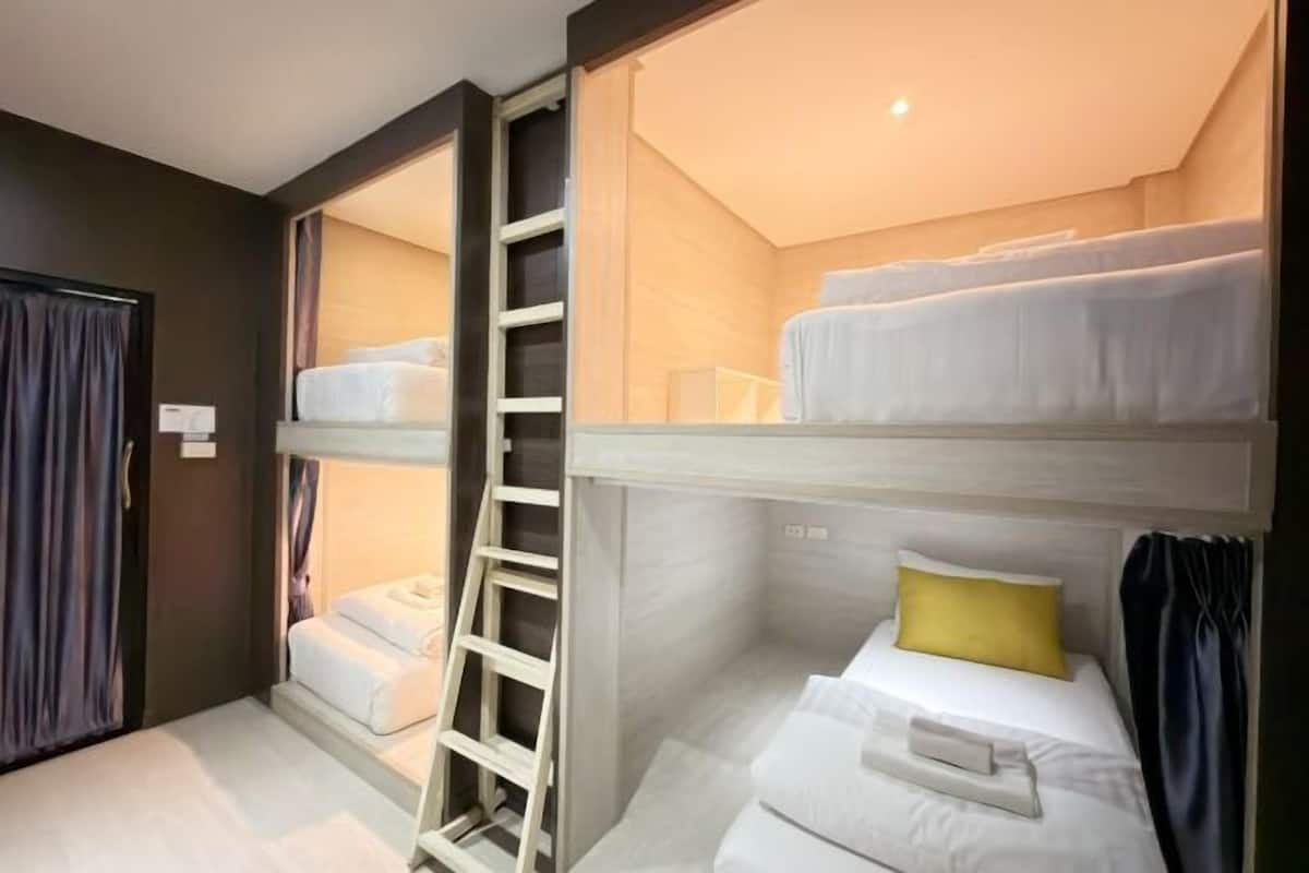 A hotel room with a bunk bed, a ladder, and a small table.