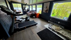 Un gimnasio en casa con equipo de ejercicio, una cinta de correr y una jaula para mascotas.