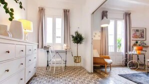 A room with a tiled floor, a desk with a chair, a sofa, a lamp, and a plant. - Boutique Living in the Heart of Barcelona (Barcelona)