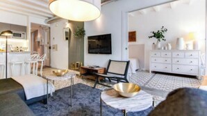 A modern living room with a sofa, a coffee table, and a dining area with a white table and chairs. - Boutique Living in the Heart of Barcelona (Barcelona)