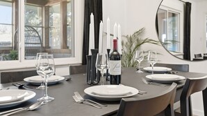 A dining table set with white plates, wine glasses, and a bottle of wine. There are candles and a mirror on the table.