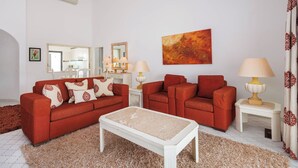 Un salon avec deux canapés rouges, une table basse blanche et un tapis beige.