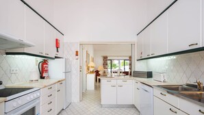 Une cuisine moderne avec des meubles blancs, un four encastré, une cuisinière et un lave-vaisselle.