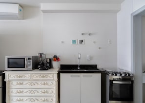 A compact kitchen with a white refrigerator, a microwave, a stove, and a white cabinet with drawers. - Apartments 110 m From the Beach in Floripa - AGC (Florianópolis)