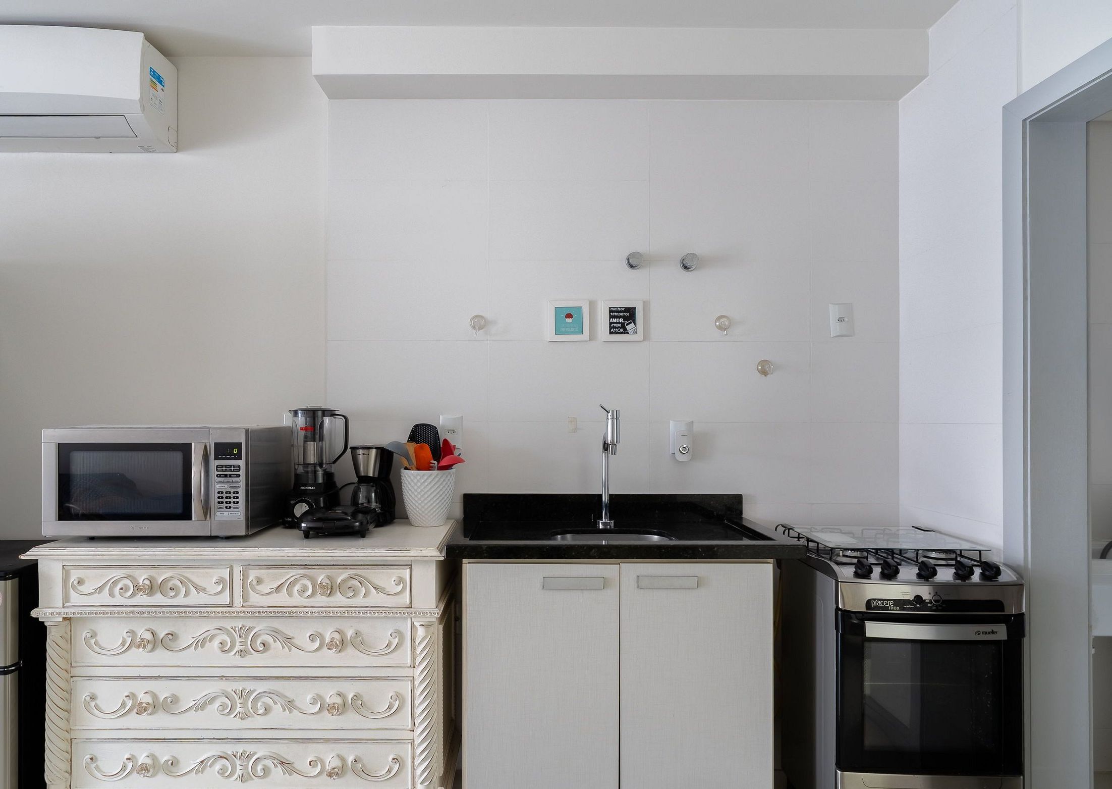 A compact kitchen with a white refrigerator, a microwave, a stove, and a white cabinet with drawers.