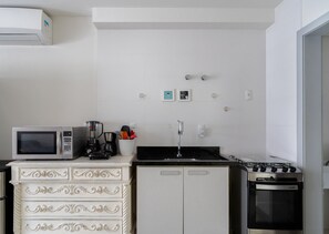 A compact kitchen with a white refrigerator, a microwave, a stove, and a white cabinet with drawers. - Apartments 110 m From the Beach in Floripa - AGC (Florianópolis)