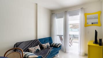 Una sala moderna con un sofá azul, una mesita amarilla y un espejo grande.