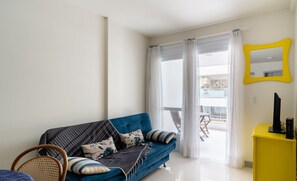 A modern living room with a blue sofa, a yellow side table, and a large mirror. - Apartments 110 m From the Beach in Floripa - AGC (Florianópolis)