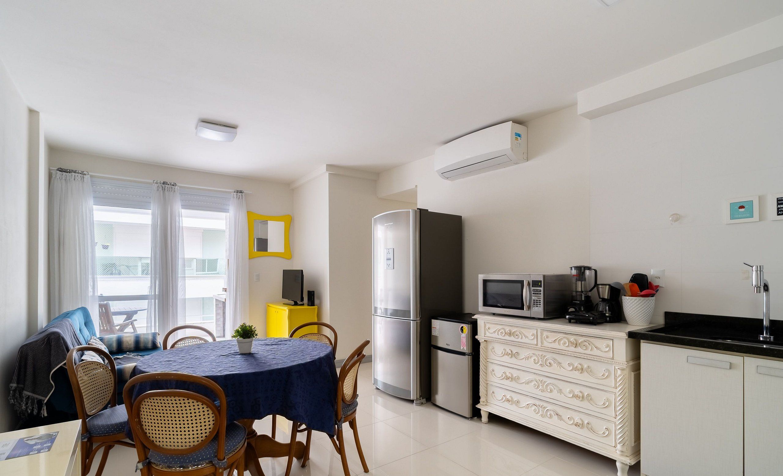 A compact living space with a dining area, kitchenette, and a small seating area with a sofa and chairs.