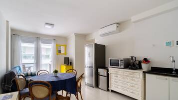 A compact living space with a dining area, kitchenette, and a small seating area with a sofa and chairs.
