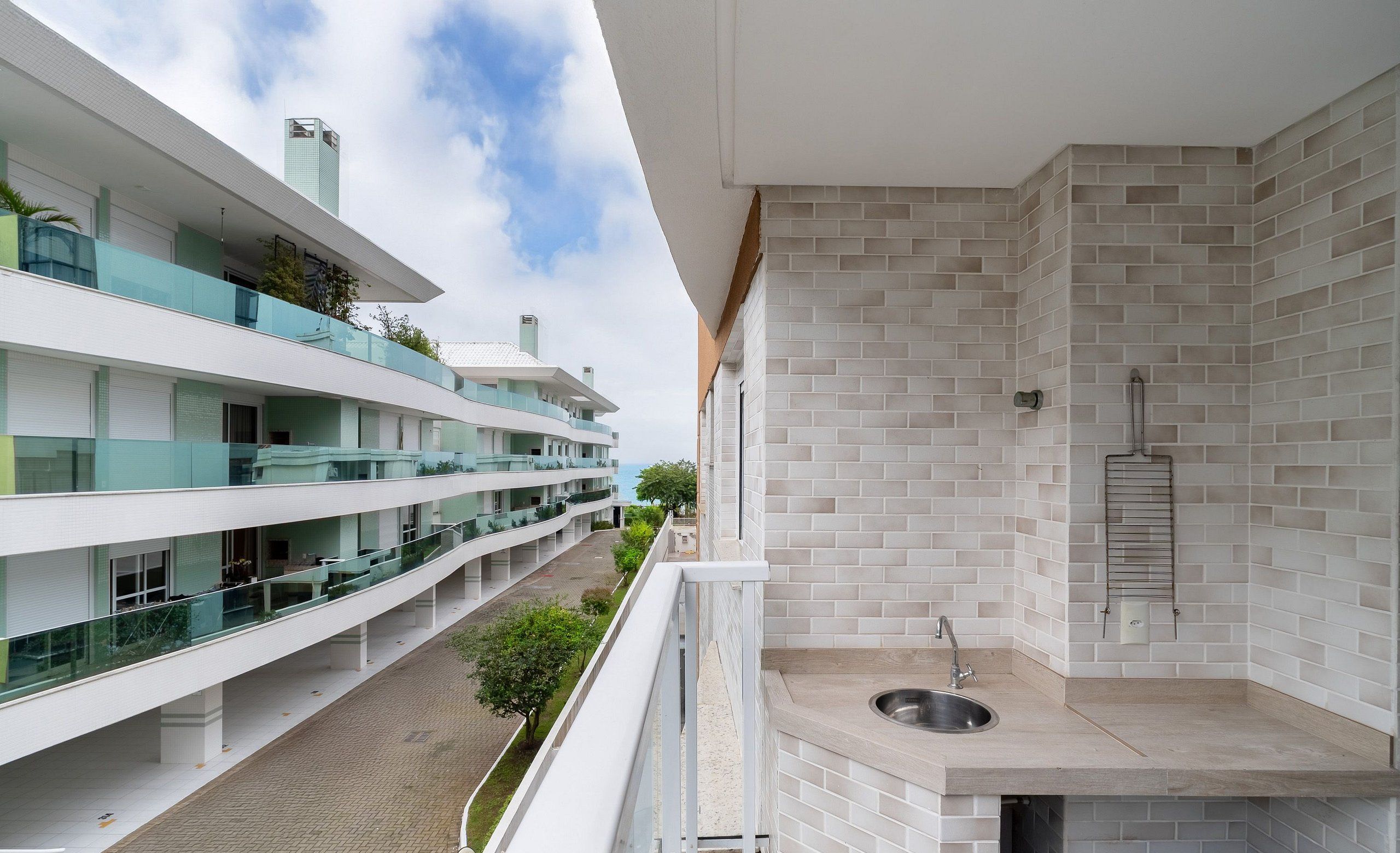 A modern apartment with a balcony, a kitchen area, and a view of other buildings.