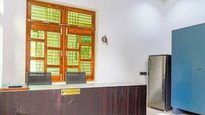 Una taquilla de recepció amb un senyal que indica zona de recepció, un armari blau i un refrigerador.