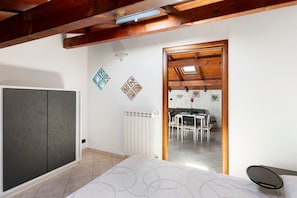 Un dormitorio con cama, armario, radiador y vistas a un comedor.