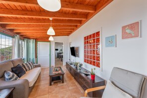 A living room with a sofa, coffee table, TV, and artwork on the wall.