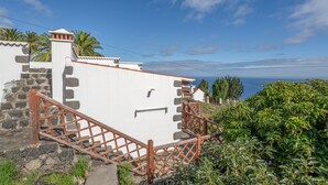 Un edificio costero con una escalera, paredes de piedra y vistas al mar.