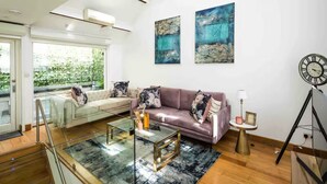 Ein modernes Wohnzimmer mit einem Glastisch, einer Ledersofa und abstrakten Gemälden an der Wand.