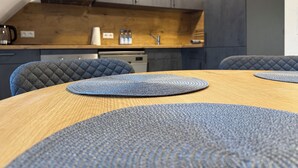 A modern kitchen with dark cabinets, a wooden countertop, and a dining table with blue placemats. - Vacation apartment Aischgrund - 75 m² | near Nuremberg, Bamberg & Steigerwald (Lonnerstadt)