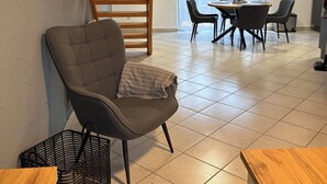 A modern living room with a grey armchair, a wooden table, and a staircase. - Vacation apartment Aischgrund - 75 m² | near Nuremberg, Bamberg & Steigerwald (Lonnerstadt)
