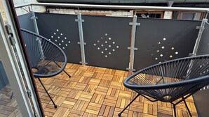 A wooden herringbone floor patio with two black wire mesh chairs. - Vacation apartment Aischgrund - 75 m² | near Nuremberg, Bamberg & Steigerwald (Lonnerstadt)