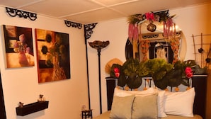 Une chambre à coucher comprenant un lit, une table de chevet, une étagère fixée au mur et deux tableaux.