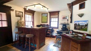 Une cuisine avec des tabourets de bar en bois, un poêle d’époque et une grande fenêtre.