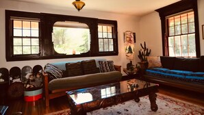Un salon confortable avec un canapé, une table basse et une fenêtre donnant sur des arbres.