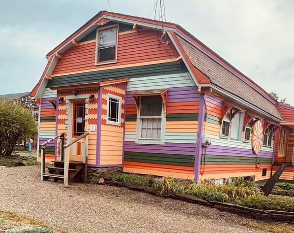 A colorful house with a gabled roof and a small porch.