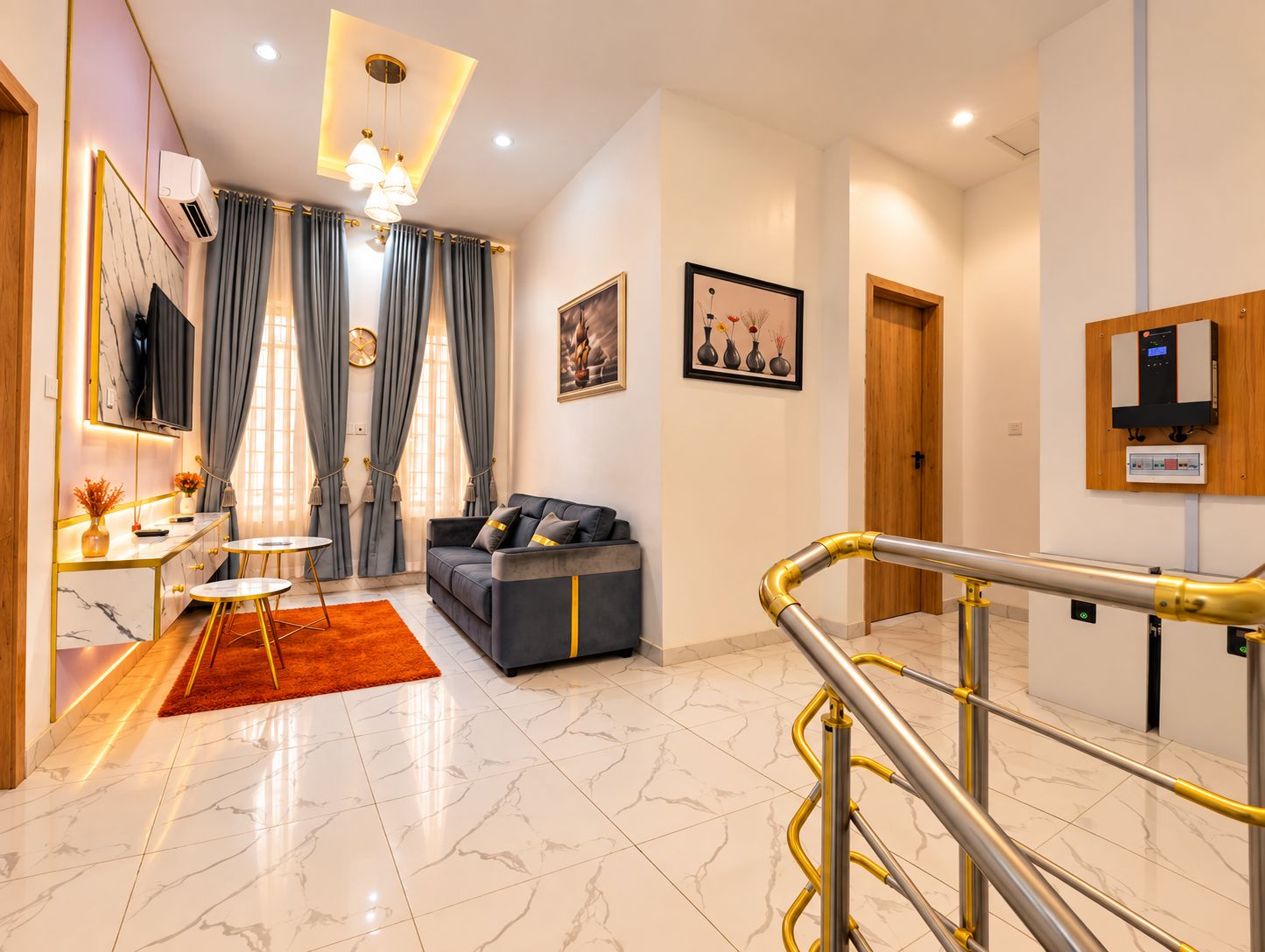 A modern living room with a sofa, a coffee table, and a TV. There is a staircase with a handrail leading to another level.